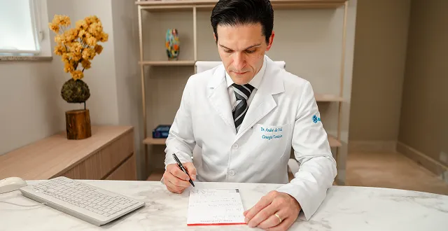 Dr. André de Val Barreto escrevendo uma orientação no consultório